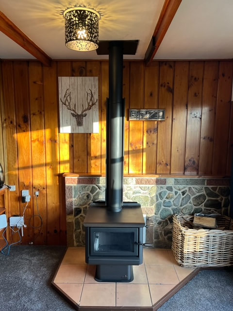 Freshly installed black wood burner in a timber-panelled Central Otago home